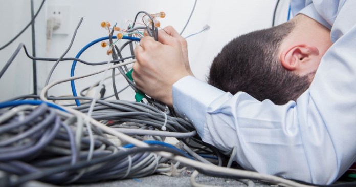 Un tipo tratando de ordenar el lío de cables de la computadora